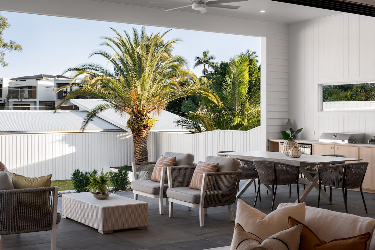 Covered outdoor alfresco with lounge setting, dining table and palm outlook